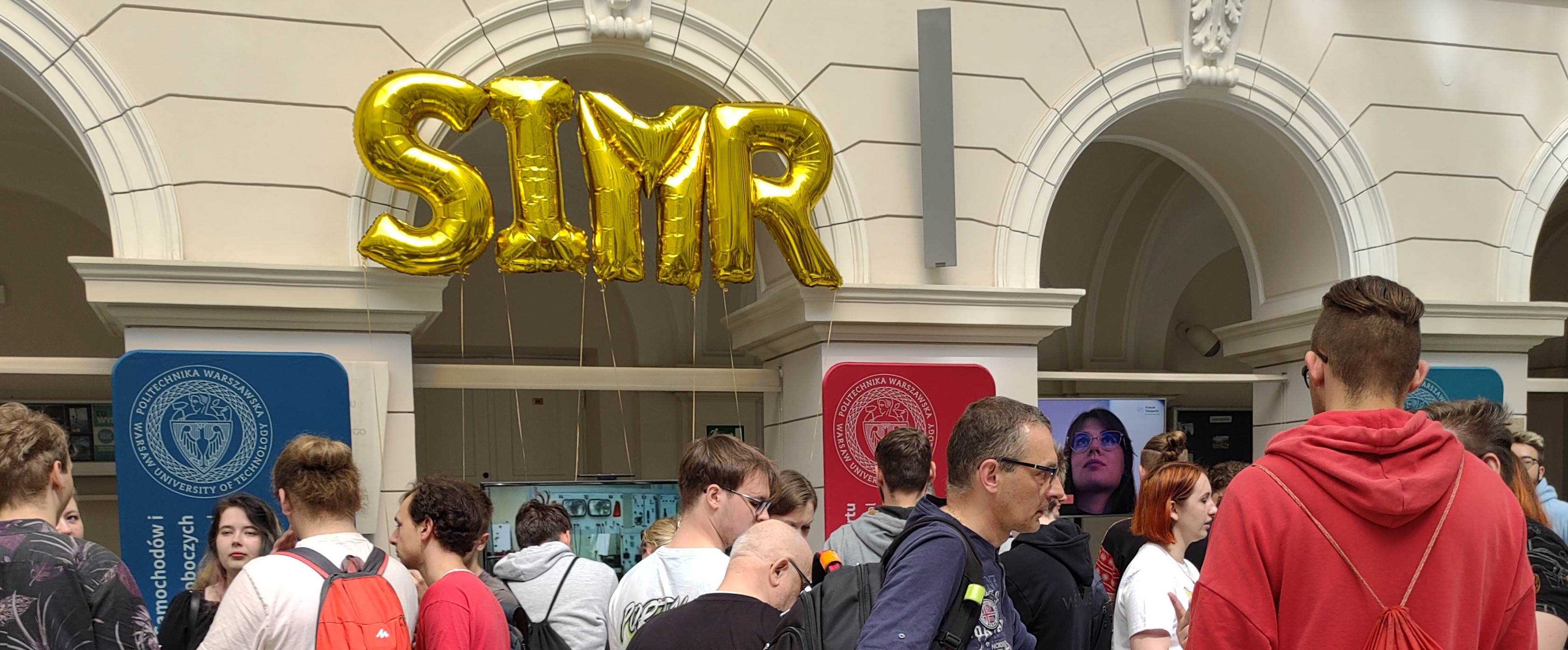 Tłum ludzi, nad nimi balony-literki układające się w napis "SIMR"