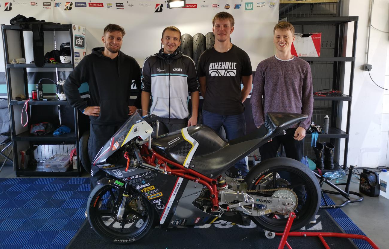 Czterech młodych mężczyzn stoi za motocyklem sportowym.
